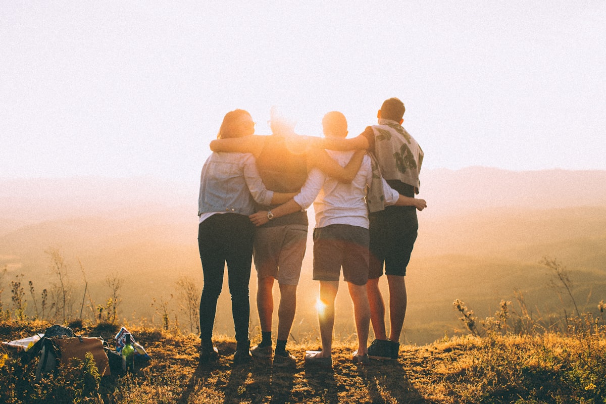 Friends with arms around each other watching the sunset together